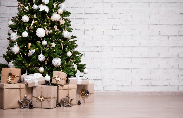 decorated christmas tree and gift boxes over white brick wall wi